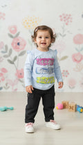 Toddler girl wearing an AllurifyYou pastel blue long-sleeve top with ruffle shoulders and black trousers